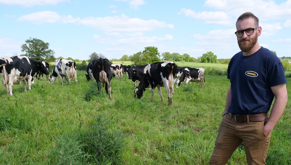 Léopold Bonthoux, jeune éleveur laitier dans un pré avec son troupeau de vaches laitières Prim'Holstein